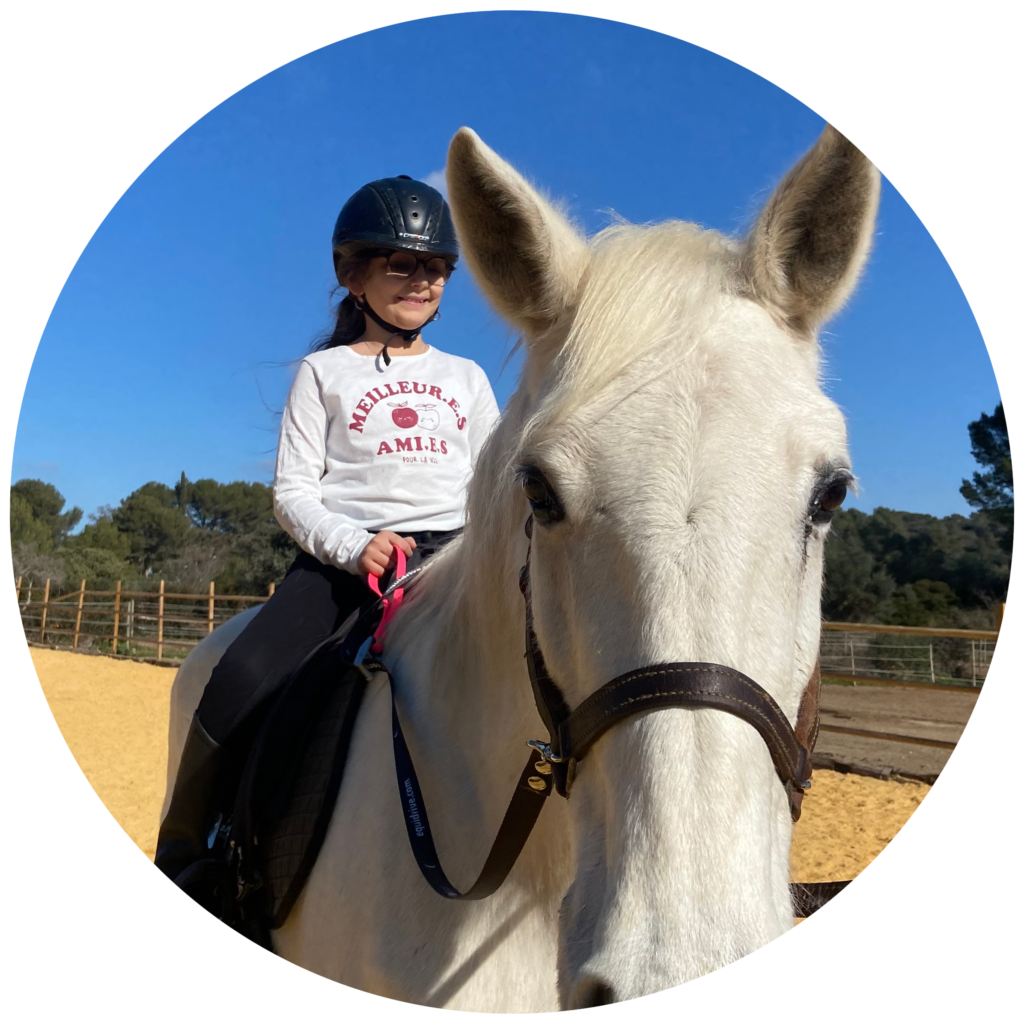 portrait de Neïla, jeune bénéficiaire, à cheval sur Karrat, un ciel bleu en arrière plan